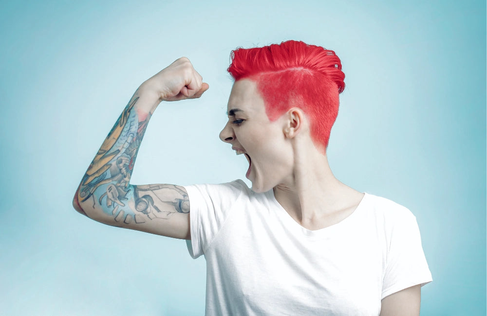 Hochmotivierte junge Frau mit rot gefärbten Haaren und Tattoo am Arm