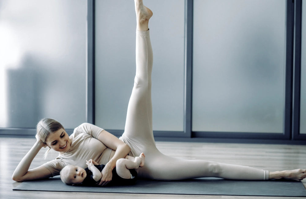Junge Mutter mit Säugling macht Yoga Übungen auf sauberer Yoga Matte
