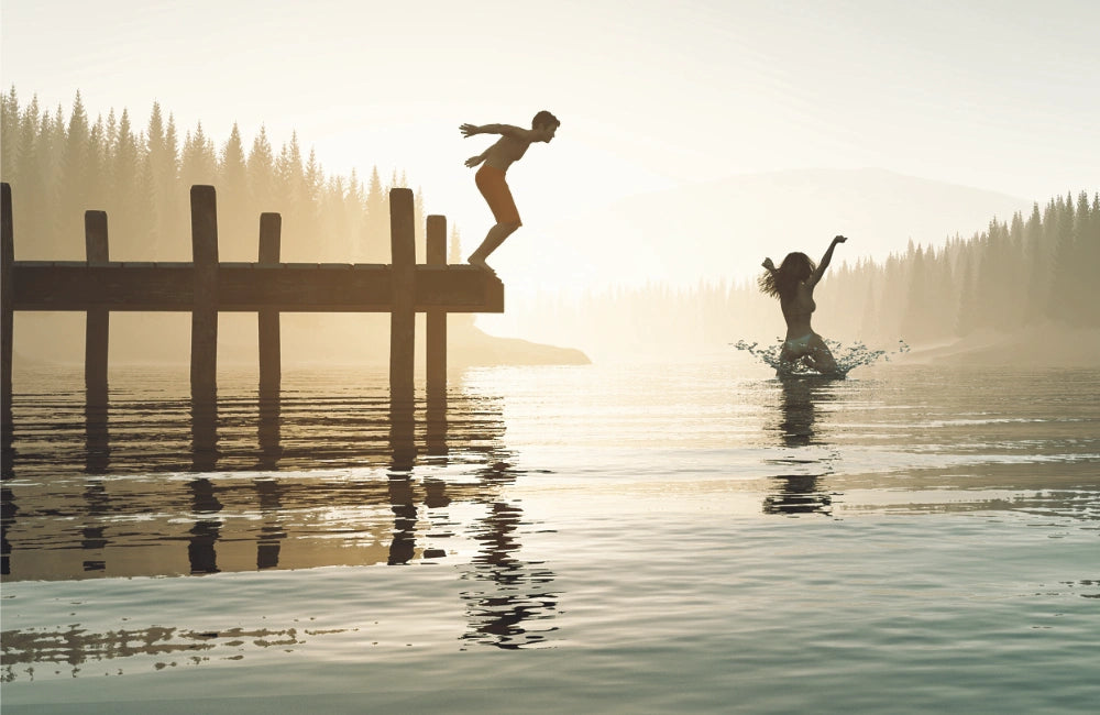 Mann und Frau springen gut gelaunt in einen kühlen See